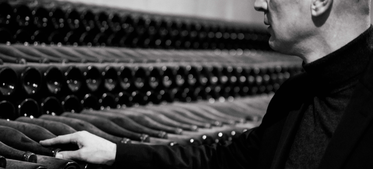 Lifestyle image of a man touching lying bottles of champagne is a cellar