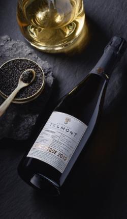 Lifestyle image of a bottle of champagne lying close to a box of caviar
